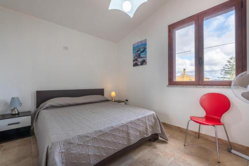 a bedroom with a bed and a red chair at Villa Giulia Grande in Castiadas