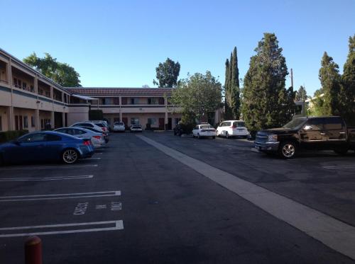 Un estacionamiento con autos estacionados frente a un edificio. en New Century Inn, en San Gabriel