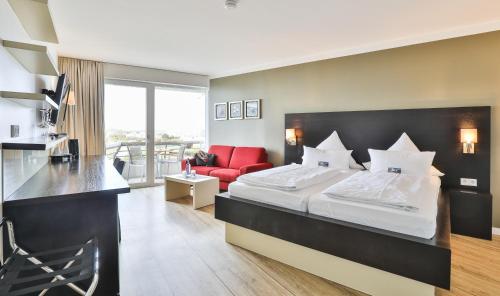 a hotel room with a bed and a red couch at Strandhotel Bene in Burgtiefe auf Fehmarn 