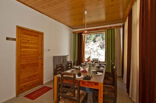 ein Esszimmer mit Tisch und Stühlen und einem Fenster in der Unterkunft THE CEDAR VILLA AND APARTMENT,Bonefire,Cook,Helper,Kitchen,Lawn,Parking,5 min Drive Mall road in Manali