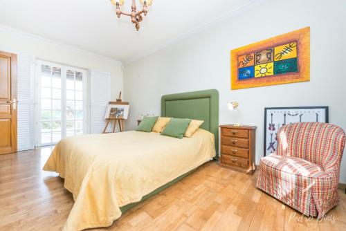 ein Schlafzimmer mit einem Bett und einem Stuhl in der Unterkunft Elegant Villa in Azeitão with Pool in Azeitão