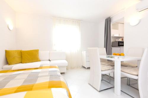 een witte woonkamer met een bank en een tafel bij One bedroom house at Skrpcici 500 m away from the beach with enclosed garden and wifi in Skrbčići