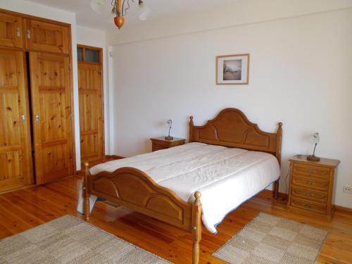 a bedroom with a wooden bed and wooden floors at 2 bedrooms villa at Pataias 700 m away from the beach with sea view private pool and enclosed garden in Pataias