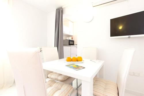 a white dining room with a white table and two oranges at One bedroom house at Skrpcici 500 m away from the beach with enclosed garden and wifi in Skrbčići