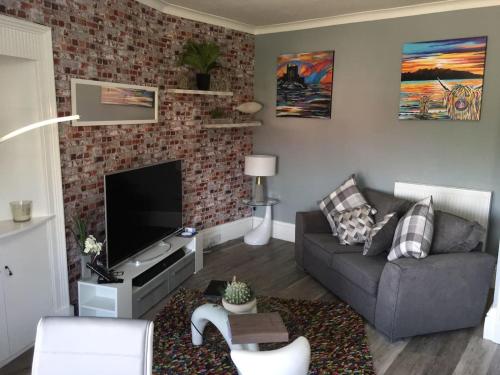 a living room with a couch and a flat screen tv at Lovely 2- Bed Apartment in Hawick in Hawick