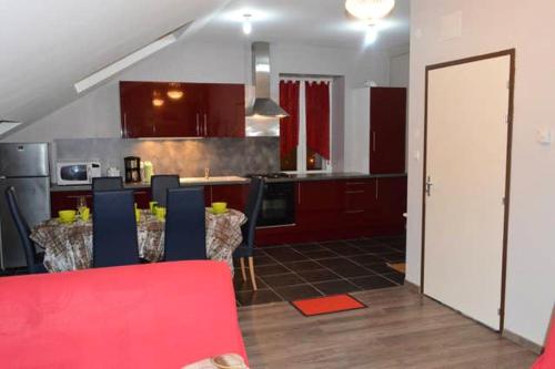 une cuisine avec une table, des chaises et un canapé rouge dans l'établissement Appartement chaleureux à Gérardmer avec parking privé., à Gérardmer