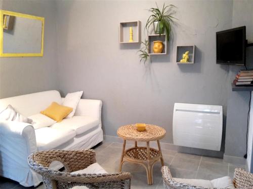 un salon avec un canapé blanc et une table dans l'établissement Appartement cosy à Villeneuve avec jardin privé, à Villeneuve-dʼAveyron