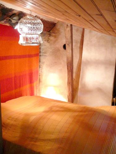 a bedroom with a wooden bed with a chandelier at Maison confortable en pleine nature près de Vesc avec jacuzzi in Vesc