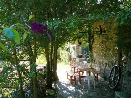 a picnic table and chairs under a tree in a garden at Maison confortable en pleine nature près de Vesc avec jacuzzi in Vesc