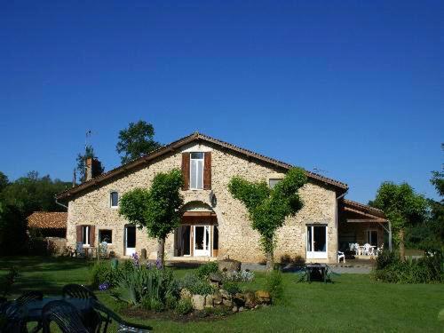 une grande maison en pierre dans une cour herbeuse dans l'établissement Appartement spacieux à Blaignac avec piscine partagée, à Blaignac