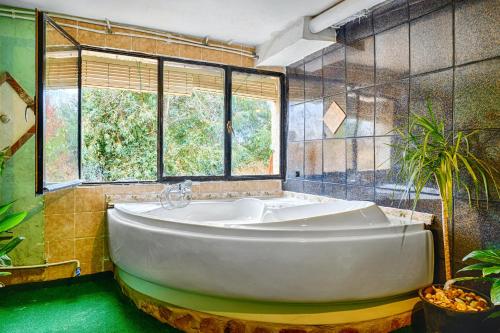 uma grande banheira na casa de banho com janelas em 3 bedrooms villa with city view private pool and jacuzzi at Porzuna em Porzuna