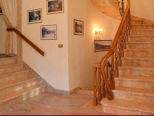 klatka schodowa w domu z drewnianymi schodami i obrazami na ścianie w obiekcie B&B Villa Adriano w mieście Cavaion Veronese