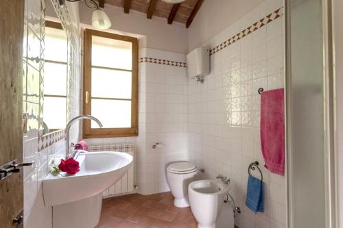 a white bathroom with a sink and a toilet at Charming Apartment in Montepulciano 45m² with shared pool in Montepulciano