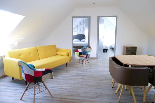 a living room with a yellow couch and chairs at Maison spacieuse à Saint-Hernin, idéale pour groupes in Saint Hernin