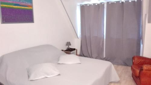 ein weißes Bett mit zwei Kissen im Schlafzimmer in der Unterkunft Maison de 2 chambres avec jardin clos et wifi a Sourdeval in Sourdeval