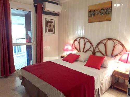 1 dormitorio con 1 cama grande con almohadas rojas en Bungalow de 2 chambres a Bouillante a 100 m de la plage avec vue sur la mer jardin amenage et wifi, en Bouillante