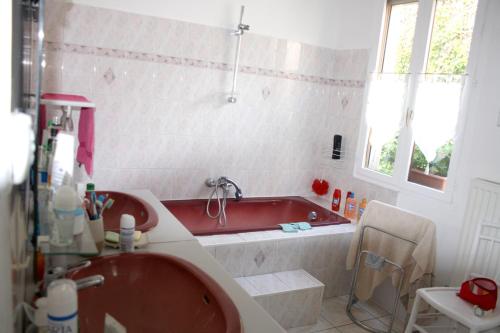 La salle de bains est pourvue d'une baignoire rouge et d'un lavabo. dans l'établissement Maison de 3 chambres avec jardin clos et wifi a Nuits Saint Georges, à Nuits-Saint-Georges
