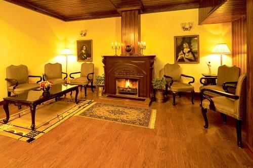 a living room with a fireplace and a table and chairs at Sinclairs Darjeeling in Darjeeling