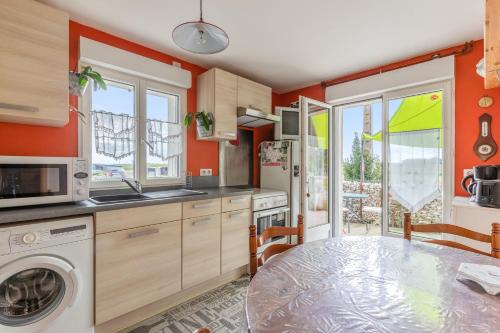 une cuisine avec des murs orange et une table avec un lave-linge dans l'établissement Appartement accueillant à Mortagne-sur-Gironde, 45 m², terrasse, à Mortagne-sur-Gironde