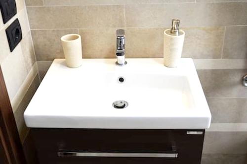 a white sink in a bathroom with two cups on it at 3 bedrooms apartement with city view shared pool and enclosed garden at Avellino in Avellino