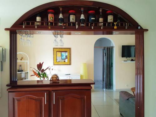 a large wooden bar in a living room with wine bottles at Maison charmante à Petit-Bourg + Jardin in Petit-Bourg
