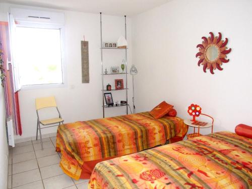 フレジュスにあるAppartement avec terrasse à Fréjus, 70 m², piscine partagéeのベッド2台と椅子と窓のある寝室