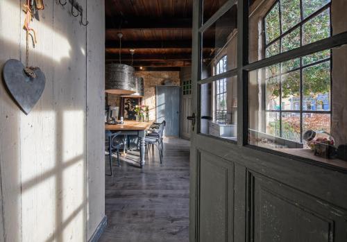 une ancienne grange avec une porte et une salle à manger dans l'établissement Smederij Texel, à De Cocksdorp