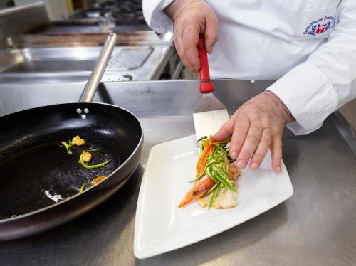a chef cutting up vegetables on a white plate at Hotel Orizzonte in Bellaria-Igea Marina