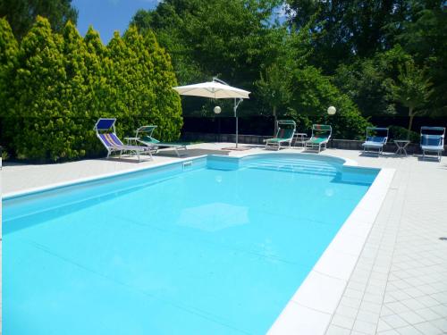 a swimming pool with chairs and an umbrella at Elegant Villa in Tuoro sul Trasimeno with Private Pool in Tuoro sul Trasimeno