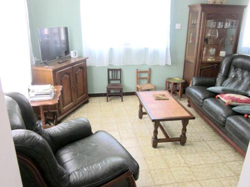 a living room with leather couches and a tv at Maison avec spa à They-Sous-Montfort, accueillant et moderne in They-sous-Montfort