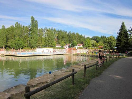 a person sitting on a fence next to a body of water at Maison avec spa à They-Sous-Montfort, accueillant et moderne in They-sous-Montfort