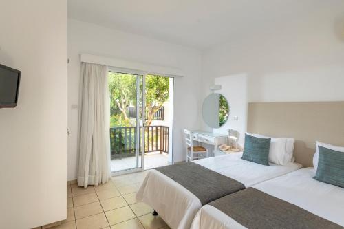 a bedroom with a large bed and a balcony at Akti Beach Hotel & Village Resort in Paphos