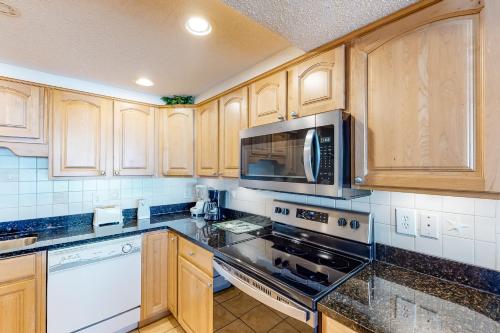 沃爾頓堡灘的住宿－Island Echos 7th Floor Condos，厨房配有木制橱柜和炉灶烤箱。