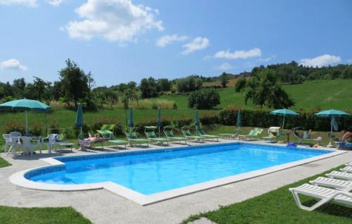a swimming pool with lawn chairs and umbrellas at 3 bedrooms appartement with shared pool enclosed garden and wifi at Caprese Michelangelo in Arezzo