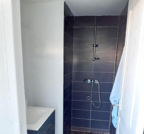 een badkamer met een douche met blauwe tegels en een wastafel bij Appartement d'une chambre avec vue sur la mer piscine partagee et jardin amenage a Saint Joseph in Saint-Joseph