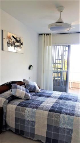 a bedroom with a bed with a blue and white blanket at Playa in Miami Platja