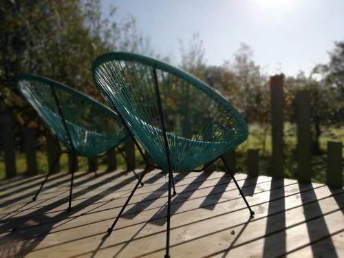 two green chairs sitting on a wooden deck at Devon Eco Lodges in Winkleigh