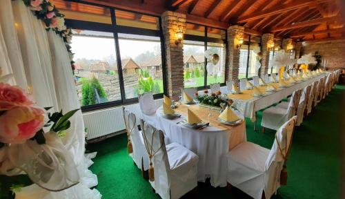 a long dining room with white tables and white chairs at Etno selo EDEN in Žeravački Potok
