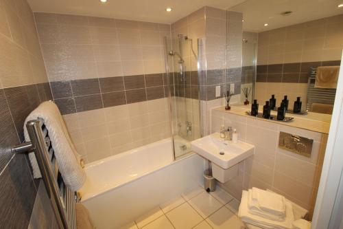 a bathroom with a tub and a sink and a shower at East Coast - Beautiful and modern holiday home in Bournemouth