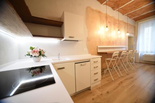 a kitchen with white cabinets and a counter with chairs at Casa Martimbola Self Check-in in Arezzo