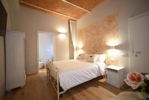 a bedroom with a white bed and a wooden floor at Casa Martimbola Self Check-in in Arezzo