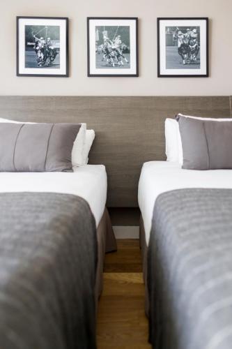 two beds in a room with pictures on the wall at CasaSur Bellini in Buenos Aires