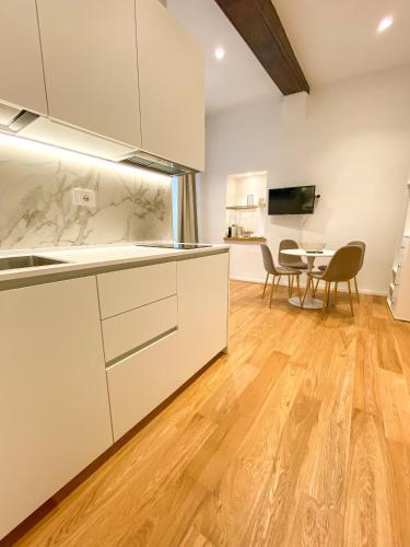 a kitchen with white cabinets and a table with chairs at La Ripa Camere Vernazza - Stradivari Luxury Apartment in Vernazza