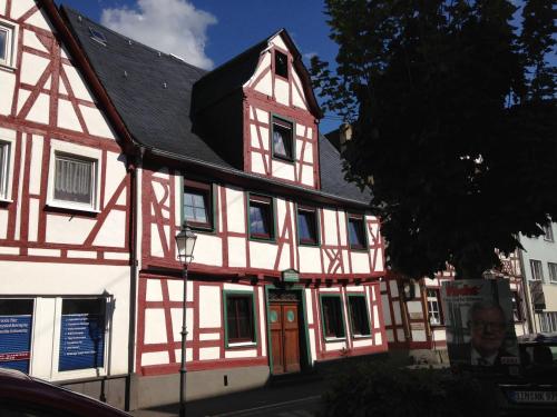 a white and red building with a black roof at AKZENT Hotel Restaurant Roter Ochse Rhens bei Koblenz in Rhens