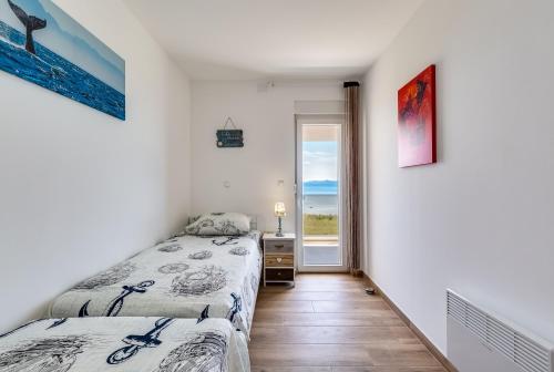 two beds in a bedroom with a view of the ocean at Beachfront villas Sun Garden by Adex Travel in Privlaka