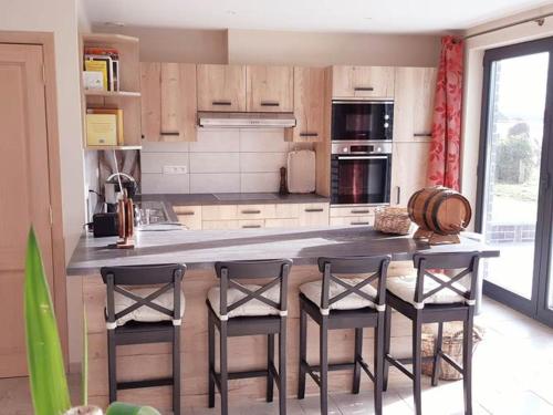 a kitchen with a counter with four chairs and a table at Le Maffe de Scourmont in Chimay