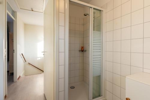ein Bad mit einer Dusche und weißen Fliesen in der Unterkunft Maxime 205 - Kustpark Village Scaldia in Hoofdplaat