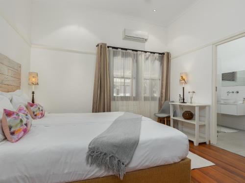 a white bedroom with a large bed and a bathroom at Abbotts Hill in Malmesbury