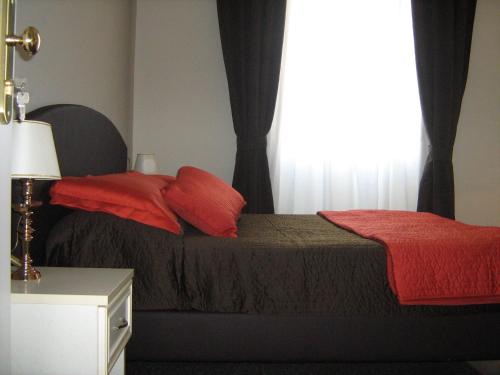 Appia Nuova Holiday B&B في روما: غرفة نوم بسرير ومخدات حمراء ونافذة