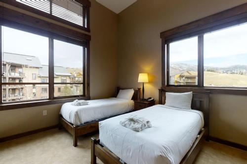 two beds in a room with large windows at Trailhead Lodge 4100 in Steamboat Springs